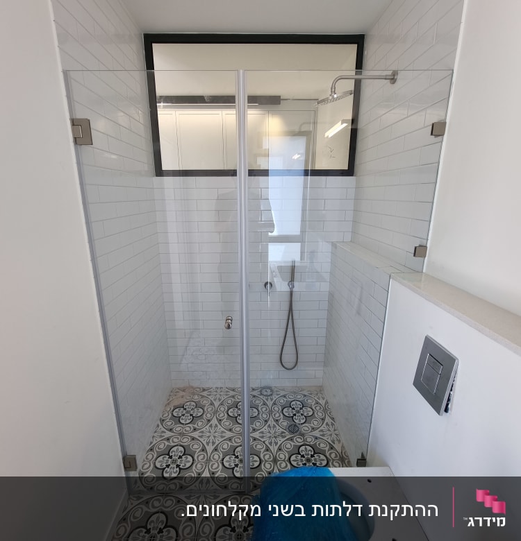 מקלחת עם דלת זכוכית, ראש מקלחת וקירות אריחים לבנים